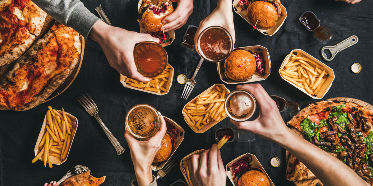 A table of gluten-free hamburgers, french fries, pizza and soda