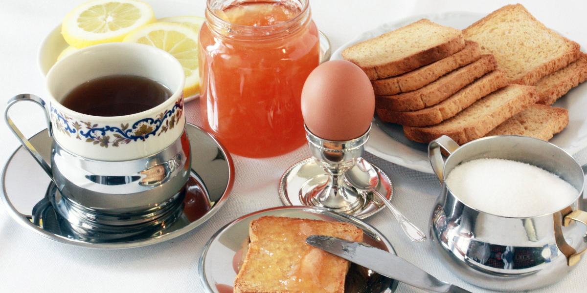 A table filled with coffee, toast, a poached egg, and gluten-free jam. 